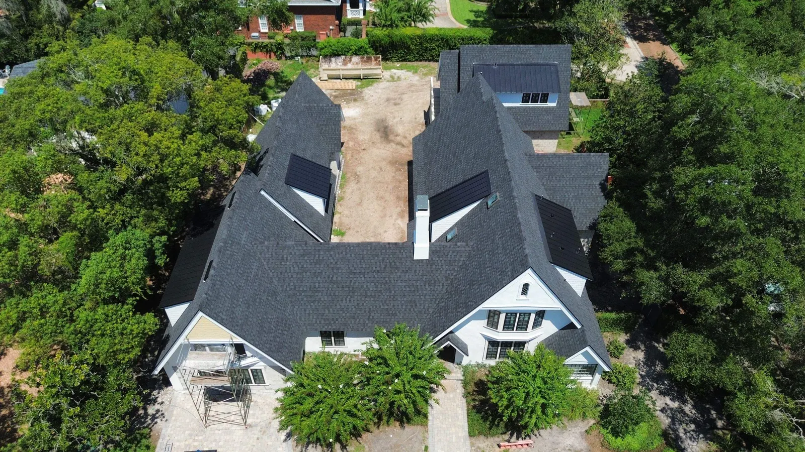 Aerial view of a steep architectural shingle roof with standing seam dormers on a historic Winter Park home