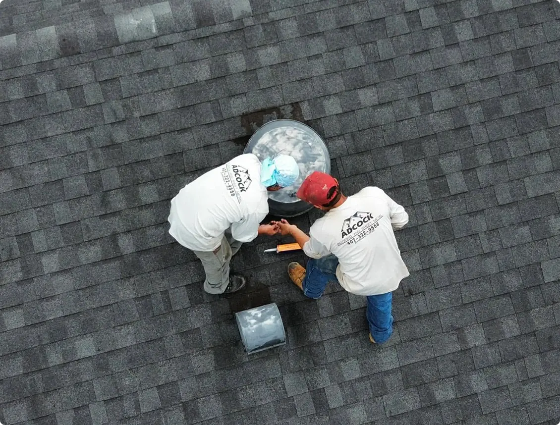 Two Adcock Roofing crew members inspecting a shingle roof from above